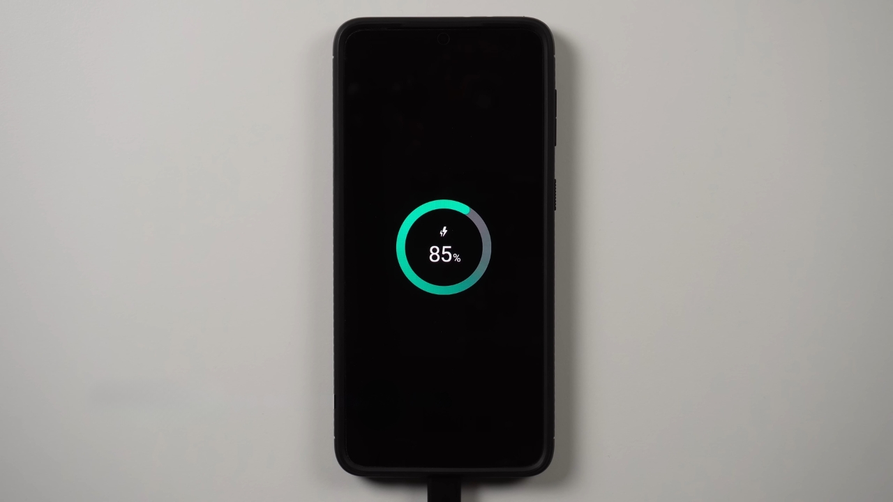 Phone connected to a charger with the battery at 85%.
