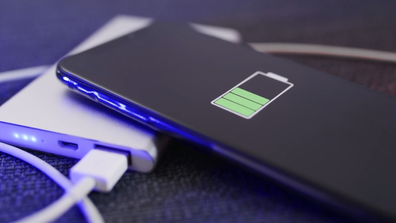 Phone beside a power bank with the battery icon on screen.